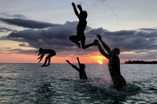 مردم در زمان غروب خورشید در سواحل تایلند تفریح می‌کنند