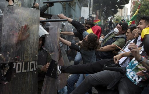مخالفان خوان اوومورالس آیما رئیس‌جمهور بولیوی در تظاهرات به سپر دفاعی ماموران پلیس در شهر لاپاز لگد می‌زنند