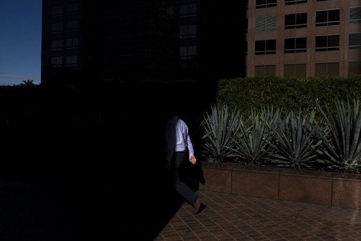 یک عابر پیاده در سایه  ایجاد  شده توسط ساختمان راه می‌رود