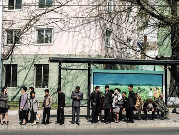 مسافران در ایستگاه اتوبوس شهر پیونگ‌یانگ  منتظر اتوبوس هستند