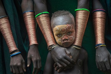 یک پسر قبیله سوری که در دره Ethiopia’s Omo اتیوپی زندگی می کند همراه زنان این قبیله است که دارای النگوهای مسی هستند