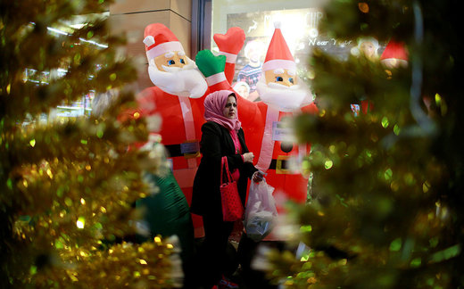 یک زن در  مقابل فروشگاه دکوراسیون کریسمس در شهر بغداد عراق