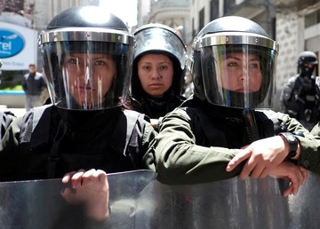 یک پلیس زن در تظاهرات روز جهانی زن مقابل ساختمان ریاست‌جمهوری شهر لاپاز بولیوی ایستاده است