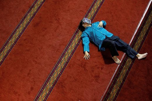 یک مرد در مسجدی در شهر جاکارتا اندونزی استراحت می کند و می‌خواهد در آنجا افطار کند