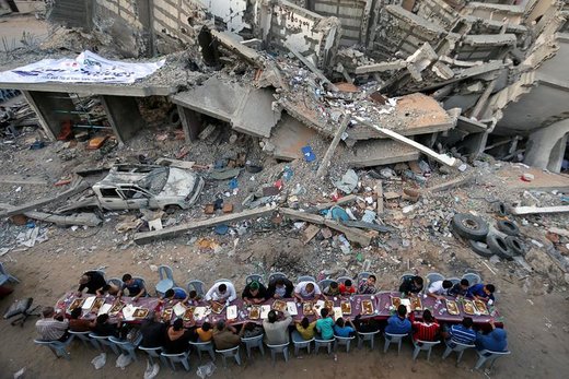 افطار کردن فلسطینی ها در ماه مبارک رمضان، نزدیک خرابه‌های ساختمان‌های شهر غزه که اخیرا توسط حملات هوایی اسرائیل تخریب شده است 