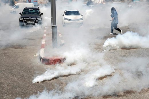 فرار عکاس زن فلسطینی از گاز اشک‌آور شلیک شده توسط نیروهای اسرائیلی در شهرک بیت‌ال کرانه غربی در جریان اعتراض به برگزاری نشست صلح  اسرائیل و فلسطین در بحرین 