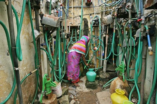 یک زن باتلمبه دستی یک ظرف را با آب آشامیدنی در شهر چنای هند پر ‌می‌کند