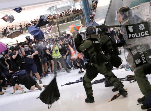 پلیس ضد شورش در داخل بازاری در هنگ‌کنگ برای متفرق کردن راهپیمایان از اسپری فلفل استفاده می‌کند 