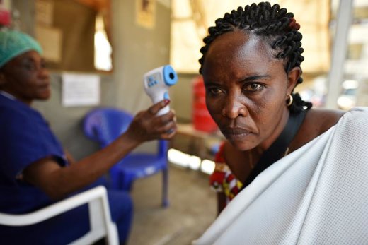 پرسنل بیمارستانی در شهر گوما کنگو به منظور شناسایی موارد احتمالی ابتلا به بیماری ابولا درجه حرارات بدن یک زن را بررسی می‌کند