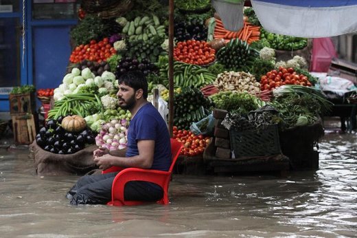 یک سبزی‌فروش پس از بارش باران و وقوع سیلاب در شهر لاهور پاکستان منتظر مشتری نشسته است