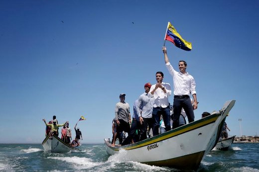 خوان گوایدو، سرکرده مخالفان دولت ونزوئلا، داخل قایقی در نزدیکی جزیره مارگاریتا برای دیدار با طرفدارانش پرچم تکان می‌دهد