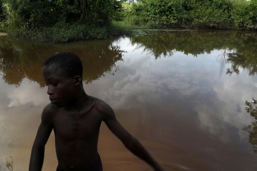 پسری در کنار رودخانهای در روستایی در ساحل عاج ایستاده است که مکان سابق برده‌داری در ساحل عاج است. زنان و مردان 400 سال پیش در ساحل عاج به بردگی گرفته و  فروخته می شدند، آنها قبل از سوار شدن به کشتی در این رودخانه برای آخرین‌بار حمام می‌کردند