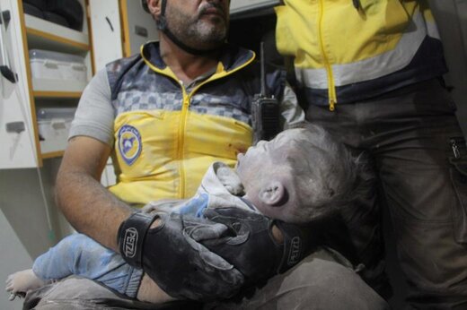 یک امدادگران بعد از حمله هوایی به معره نعمان استان ادلب سوریه، یک کودک را که از زیر آوار بیرون آورده شده، در آغوش گرفته است