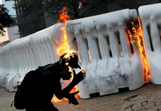یک معترض ضد دولتی در تظاهراتی در نزدیکی مقر دولت مرکزی در هنگ‌کنگ چین  بمب‌بنزینی را پرتاب می‌کند 