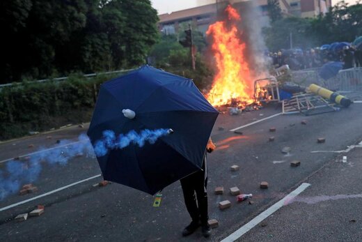 یک معترض ضد دولتی در جریان تظاهرات در هنگ‌کنگ، پشت چتر قرار گرفته است