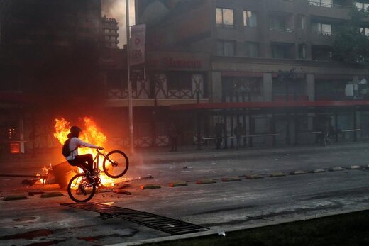دوچرخه سواری یک تظاهرکننده در اعتراضات نسبت به افزایش قیمت بلیط مترو در سانتیاگو  شیلی 