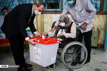 عکس | بانوی سالمندی که با قابی از حاج قاسم پای صندوق رای رفت