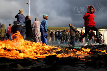 تخریب خانه‌های مردم در یک سکونتگاه غیررسمی در کیپ‌تاون آفریقای جنوبی جهت ساخت برج‌های بلندمرتبه، اعتراض ساکنین را در پی داشت؛ اعتراضاتی که به صورت پراکنده با آتش‌افروزی همراه بود. در این تصوی فرار یک پسربچه از موانع در حال سوخت را می‌بینید