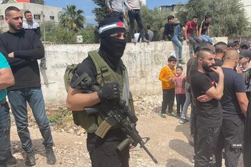 عکس | هدیه چریک مبارز فلسطینی به یک پسربچه در کمپ پناهندگان