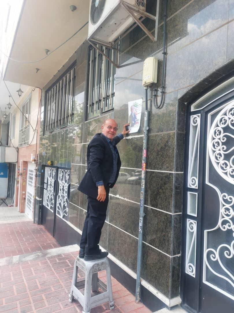 عکسی از استاد دانشگاه شریف هنگام چسباندن پوستر مسعود پزشکیان به دیوار