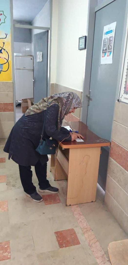 عکسی از همسر مصطفی تاج زاده به همراه یک پلاکارد پای صندوق رأی