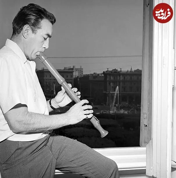 عکس/ «آنتونی کوئین» در حال نواختن فلوت در کنار پنجره خانهاش؛ سال ۱۳۳۵