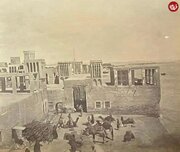 کارگران جنوبی در حال خالی کردن بار شترها در بندر لنگه؛ سال ۱۲۸۸